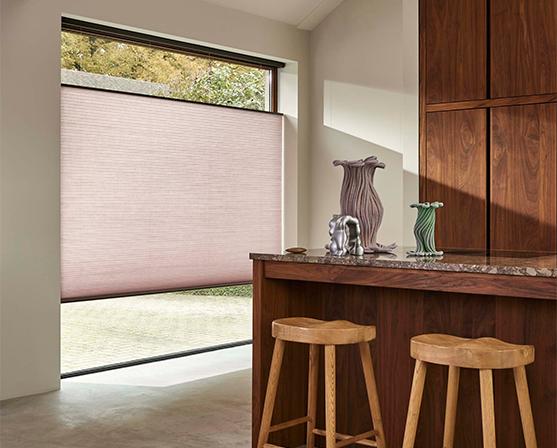 luxaflex duette shades roze groot raam keuken roze plisségordijnen walnoot houten kookeiland barkrukken