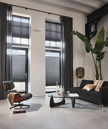 Luxaflex plisségordijnen en zwarte gordijnen modern chique interieur hoge ramen gietvloer betonvloer eames chair