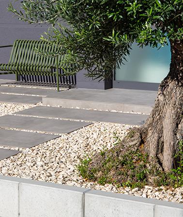 Tuin grind grote terrastegels olijfboom groene tuinbank draadstaal