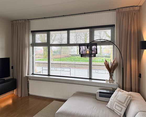 Woonkamer Verano houten jaloezieën 50 mm bamboe bruin en A House Of Happiness gordijnen Maran Zand 22