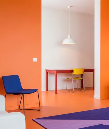 Dopamine decor interieur oranje muren blauwe stoel gele stoel rode tafel paars vloerkleed witte hanglamp