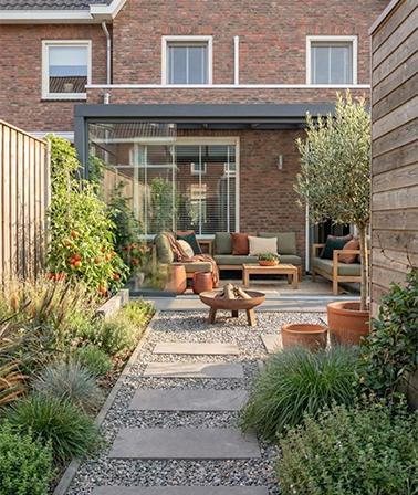 Tuintrend 2026 achtertuin rijtjeshuis aluminium overkapping glazen schuifwanden low dining set grind statpstenen borders planten
